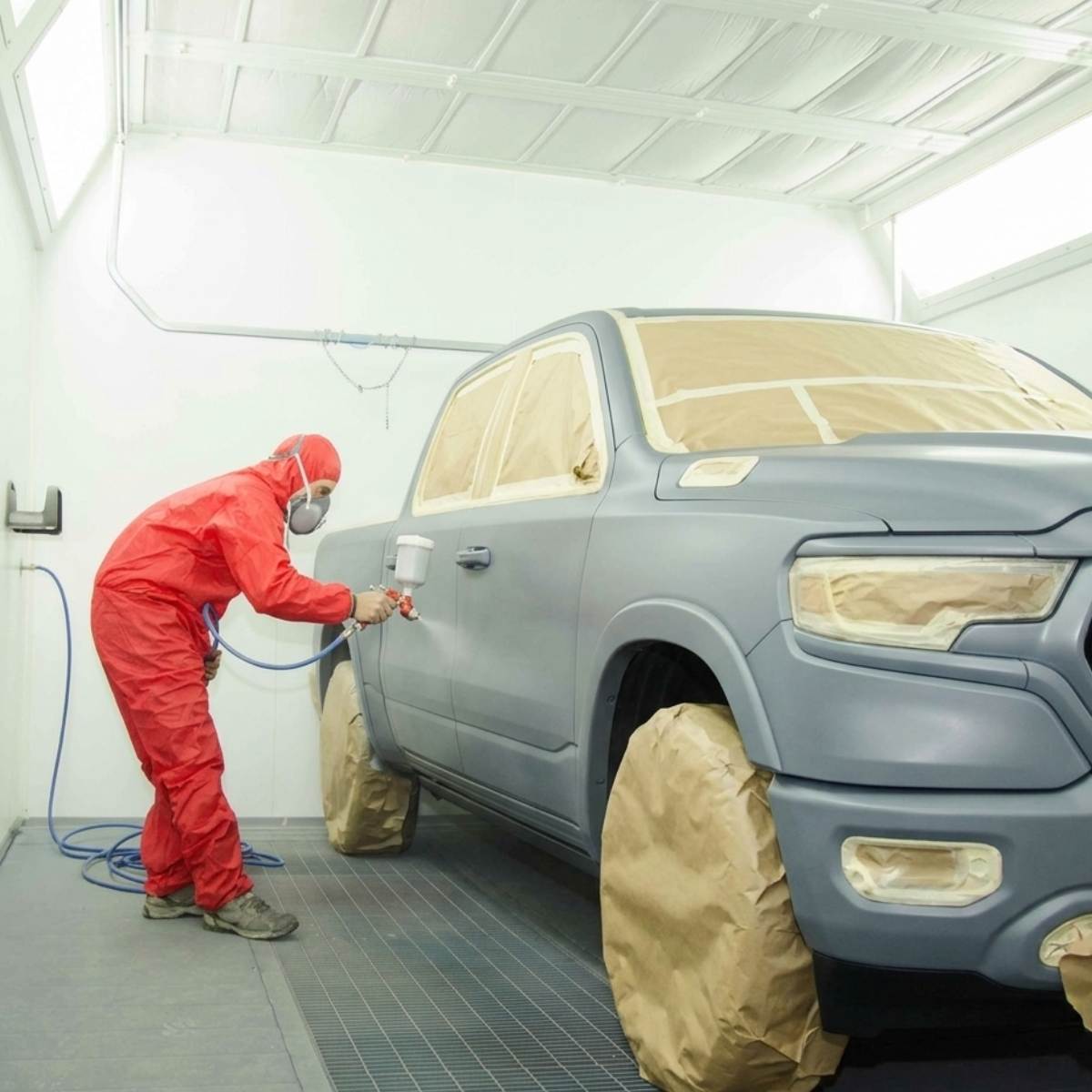 fender repair tech painting truck in paintbooth